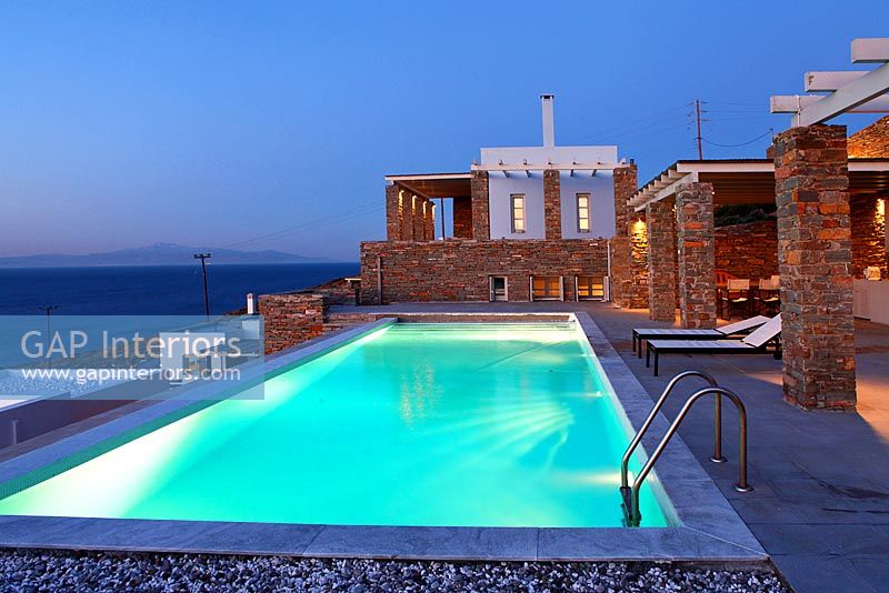 Modern villa and swimming pool lit up at night
