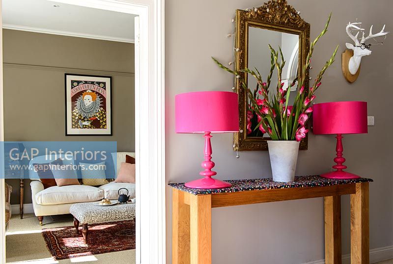 Pink Gladioli and lamps on console table