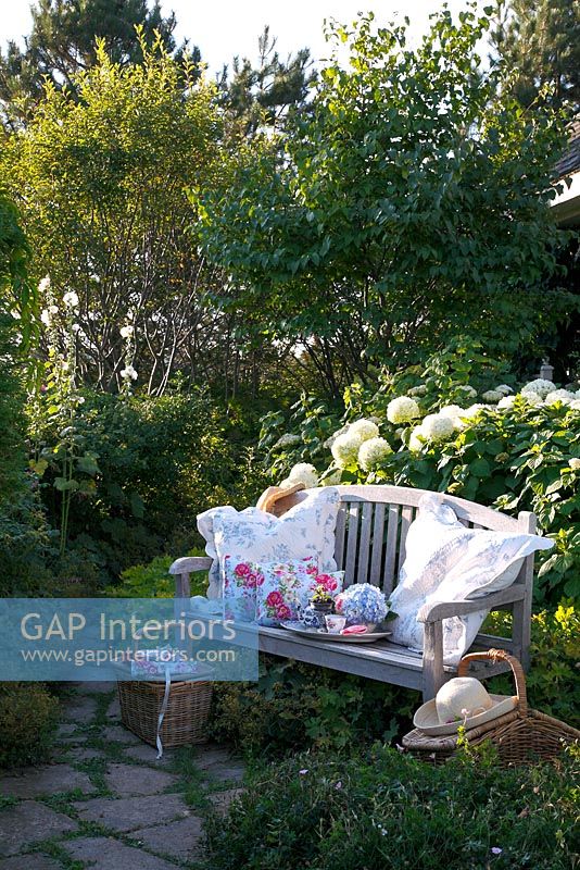 Wooden bench with floral cushions and accessories