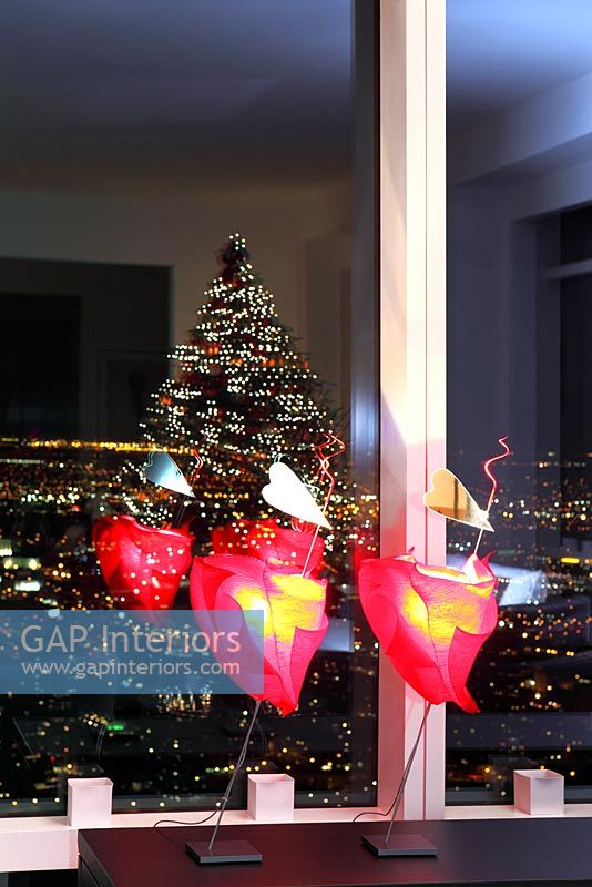 Modern lighting and christmas tree reflected in window
