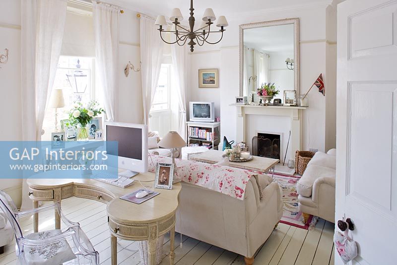 White sitting room with vintage dressing table and linen sofas