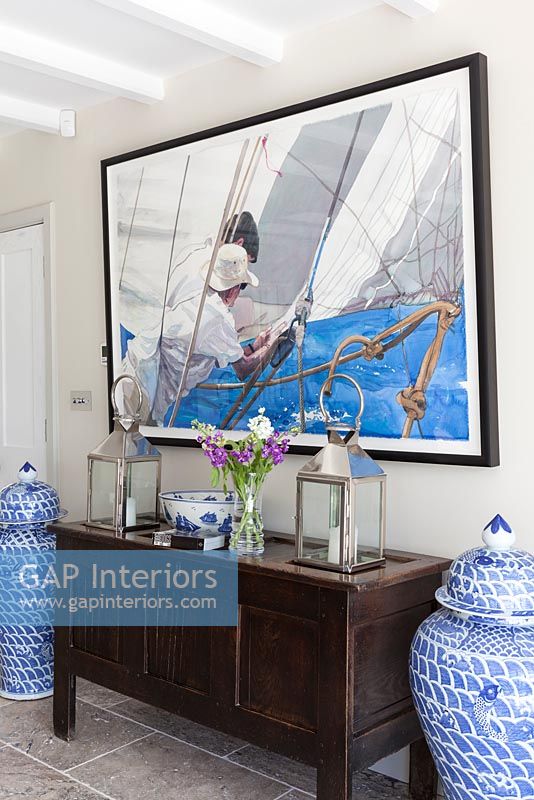 Nautical painting above wooden sideboard