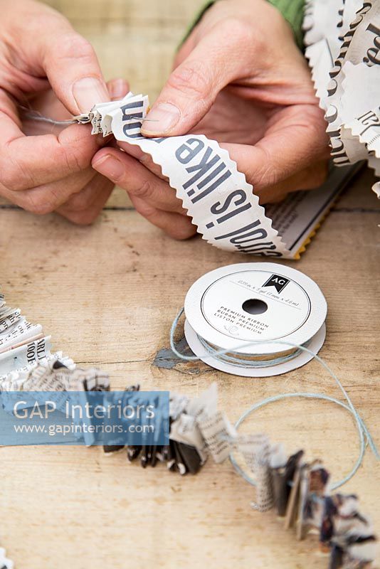 Creating a simple Christmas wreath using newspaper and  wire - threading newspaper onto string