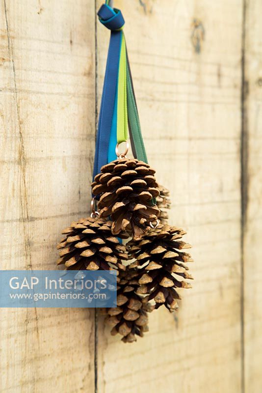 Christmas decorations made with pine cones and ribbon hanging from wooden door