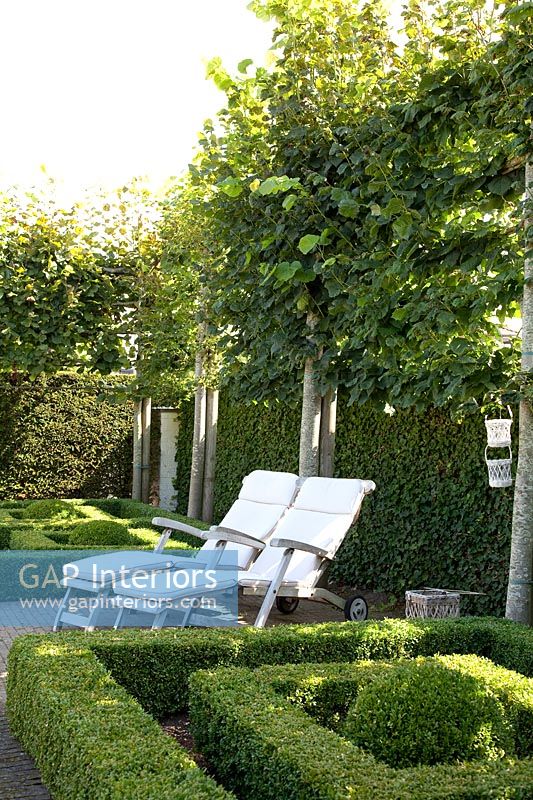 Formal parterre garden with white loungers