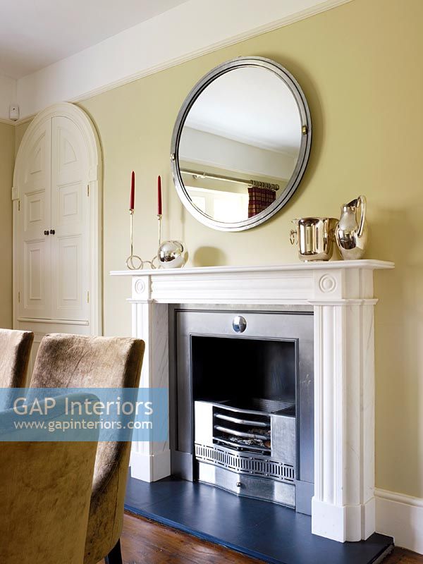Round mirror above fireplace