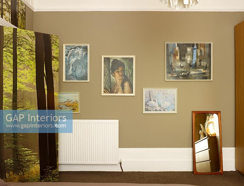 Display of paintings on bedroom wall