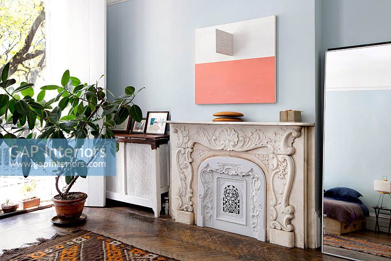 Abstract painting above ornate fireplace