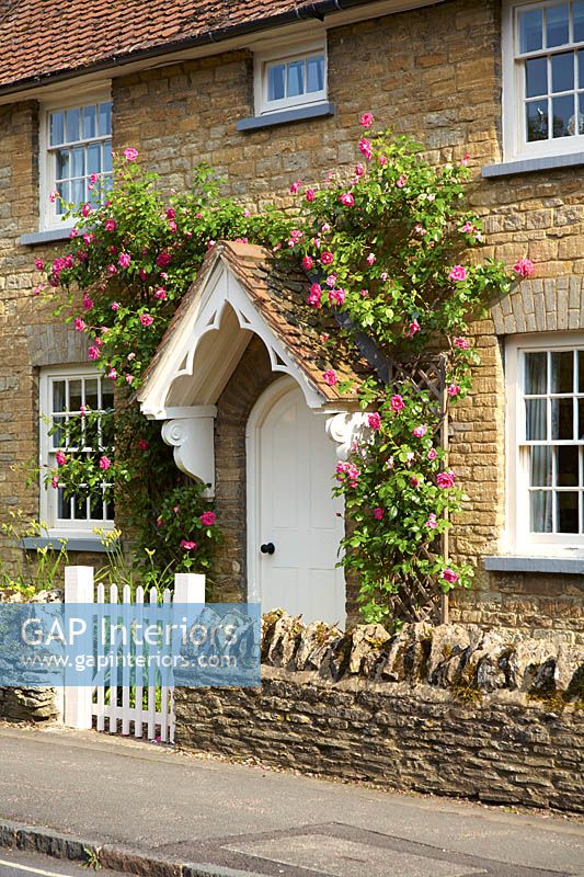 Cottage front door with Roses growing around porch
