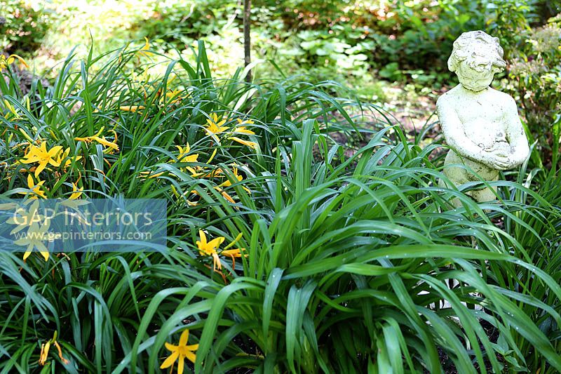 Garden border with Daylilies and sculpture