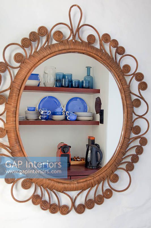 Blue crockery reflected in cane mirror