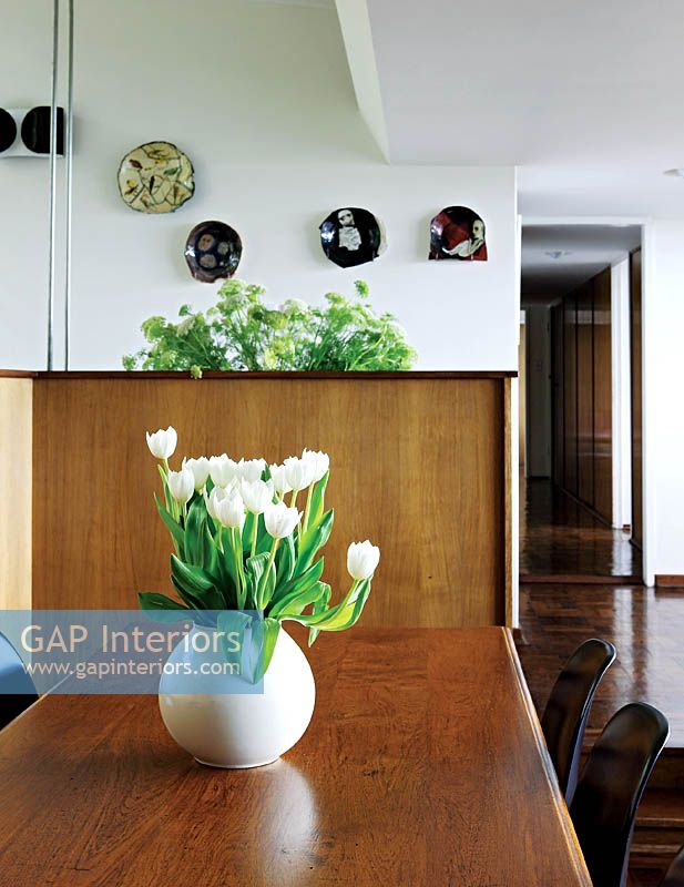 Vase of white Tulips on wooden dining table