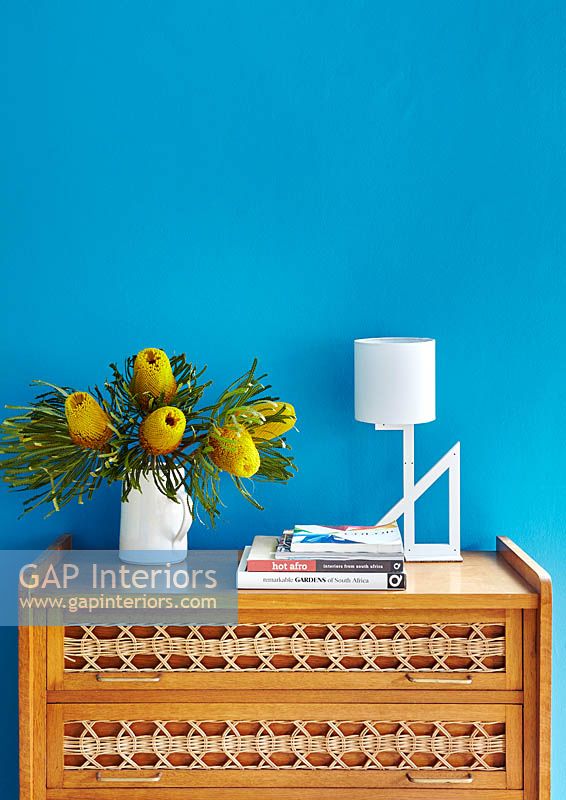 Jug of tropical flowers on wooden chest