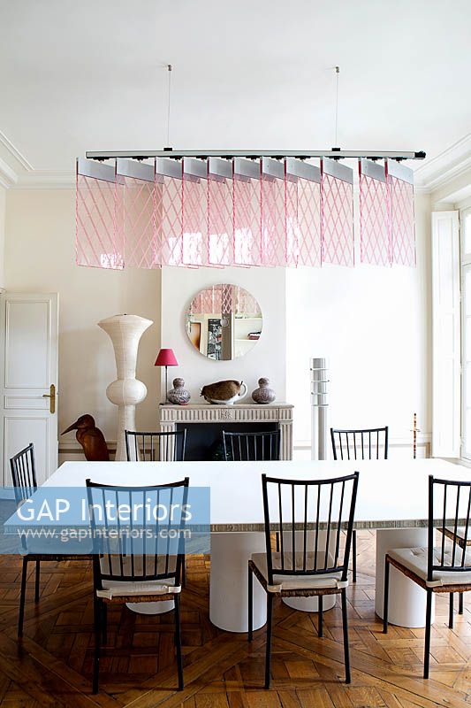 Modern dining room with designer furniture and pink suspended light by Johanna Grawunder
