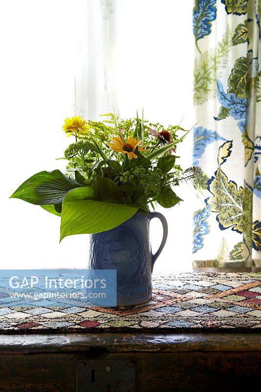 Colourful flowers and foliage in blue jug