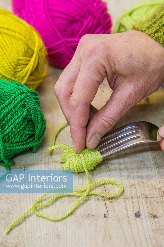 Making christmas pompom decorations - Gently remove the bundle of wool from the fork