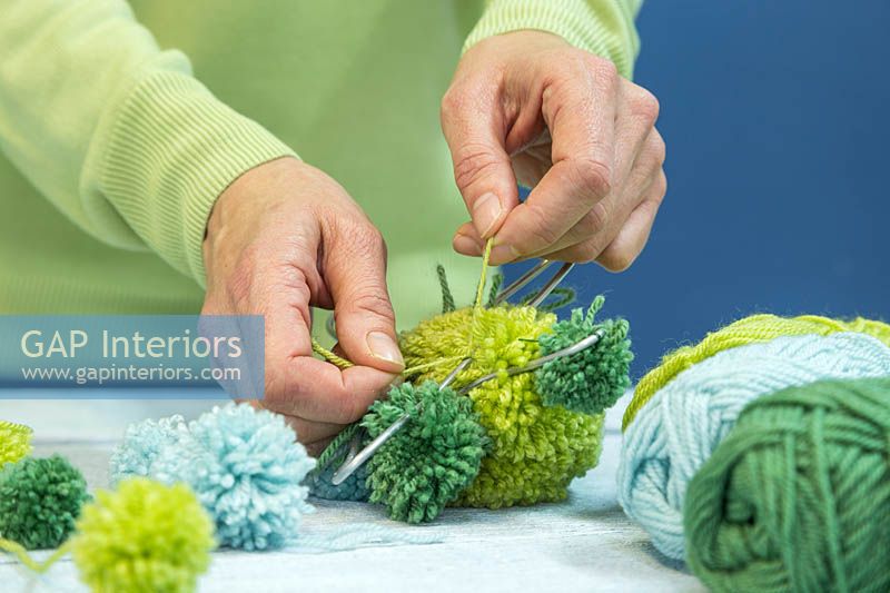 Making a pompom star decoration - Tying wool pompoms to a metal frame in the shape of a star