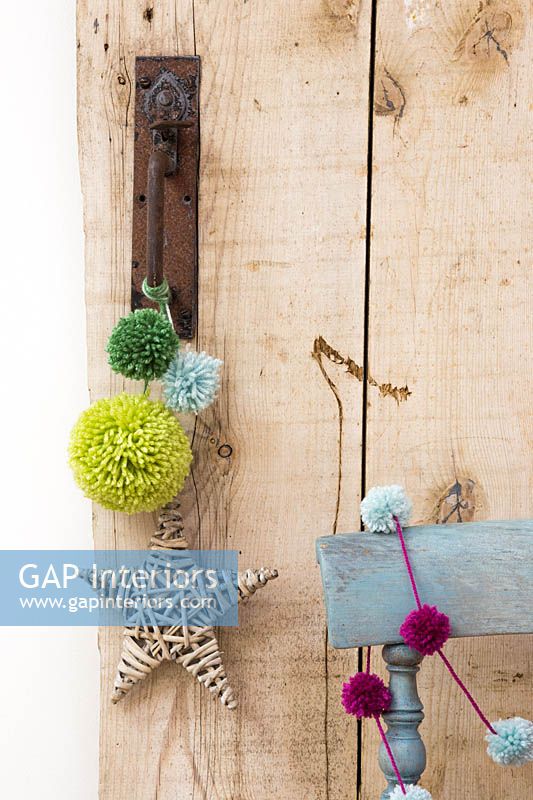 Wool pompoms in different sizes hanging from a door handle