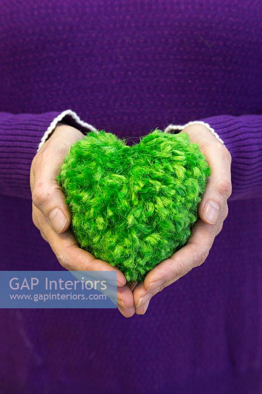 Woman holding green heart pompom made from wool