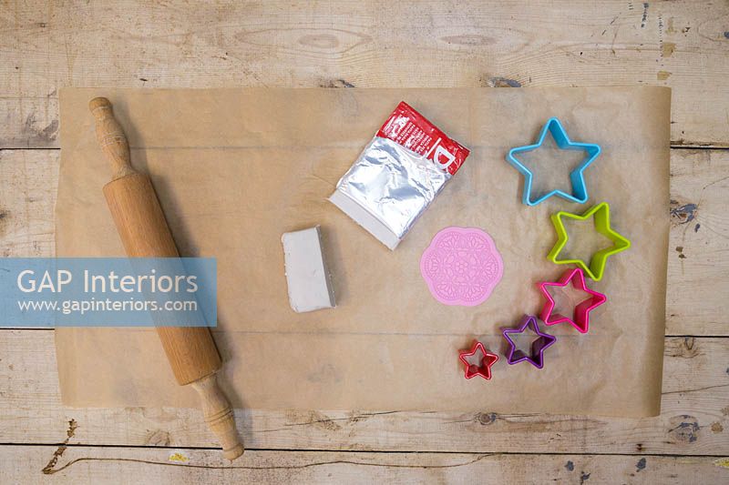 Making clay stars - Materials required are white modelling clay, silicone flower mould, star shape cutters, string, scissors, rolling pin and a skewer