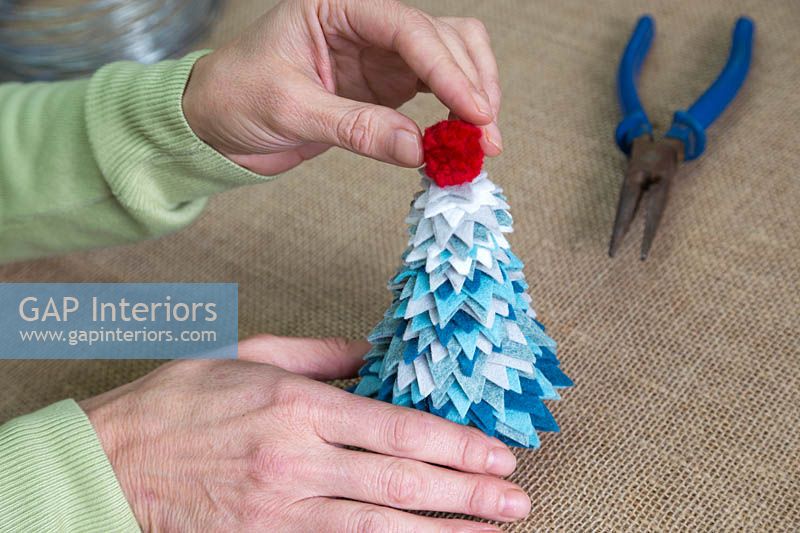 Making a felt christmas tree - Add the pom pom to the top of the tree to finish it off 