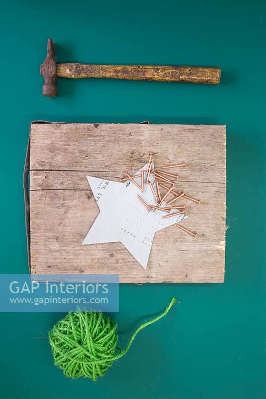Making a christmas star decoration - Materials required are green wool, hammer, copper nails, star template and a square section of wood