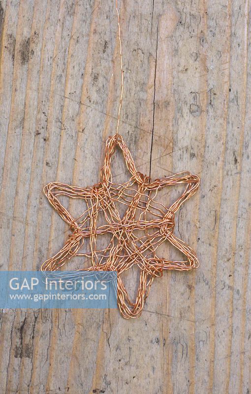 Making copper wire stars - finished decorations on wooden surface