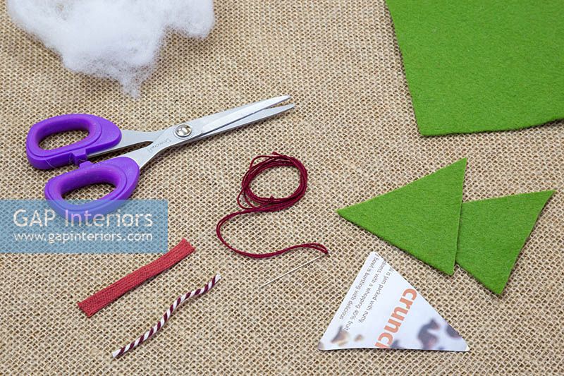 Making stitched felt christmas decorations - Materials required are scissors, felt, needle and thread, wool, triangle template and decorative string