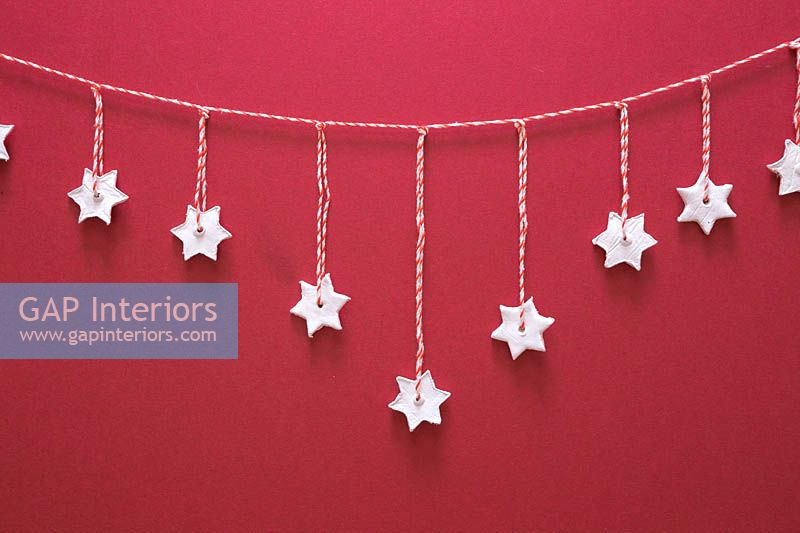 Miniature clay stars hanging from red and white striped string