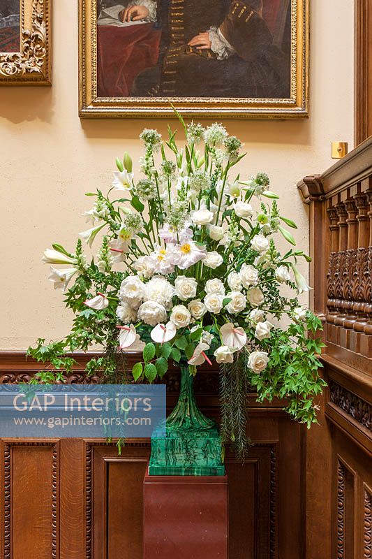 Floral display on oak staircase with Allium 'Mount Everest' and Peony 'Duchesse de Nemours' flowers in malachite vase