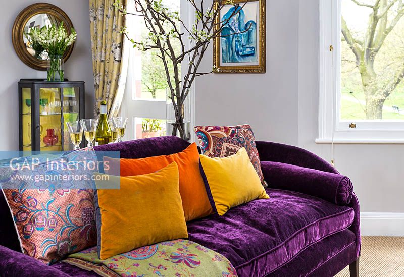 Colourful soft furnishings on purple sofa