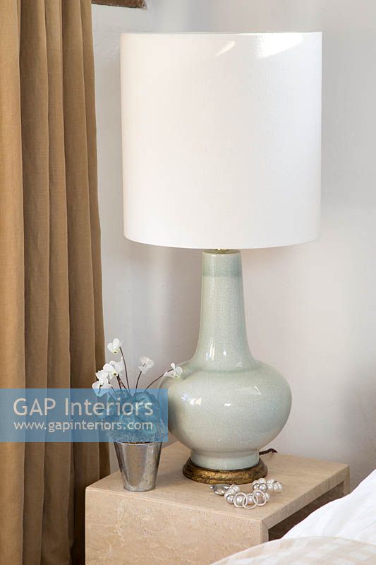 Modern lamp and potted Cyclamen on bedside table