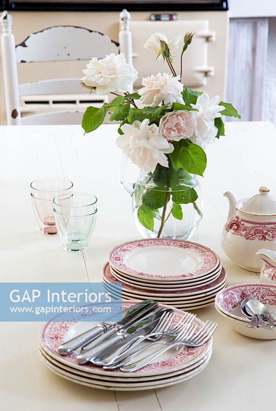 Classic tableware and vase of Roses on kitchen table