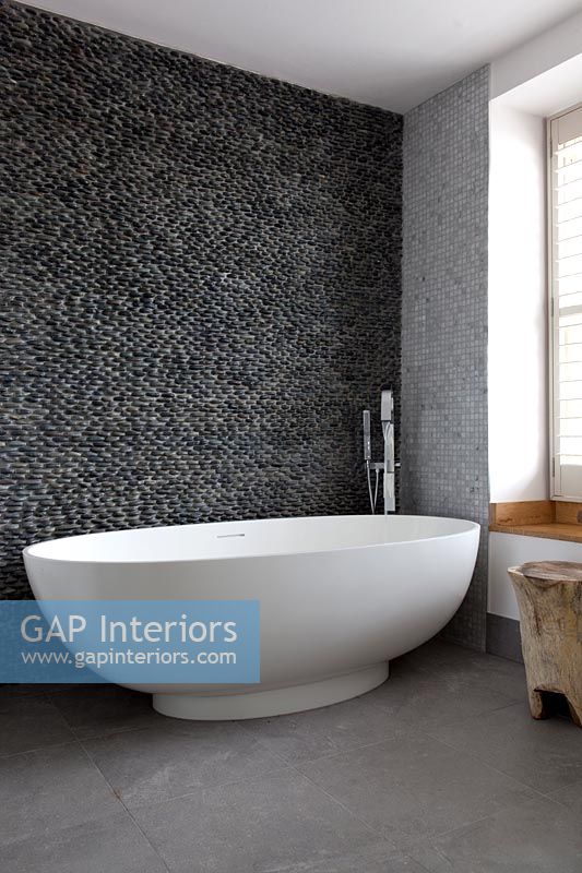 Contemporary bath with pebble wall 