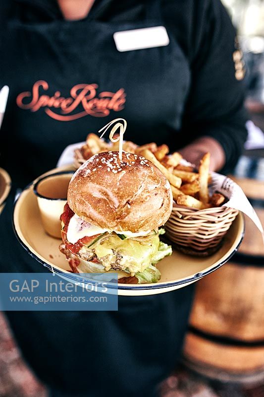 Waitress carrying plate of burger and chips