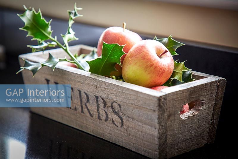 Apples and holly foliage in wooden container