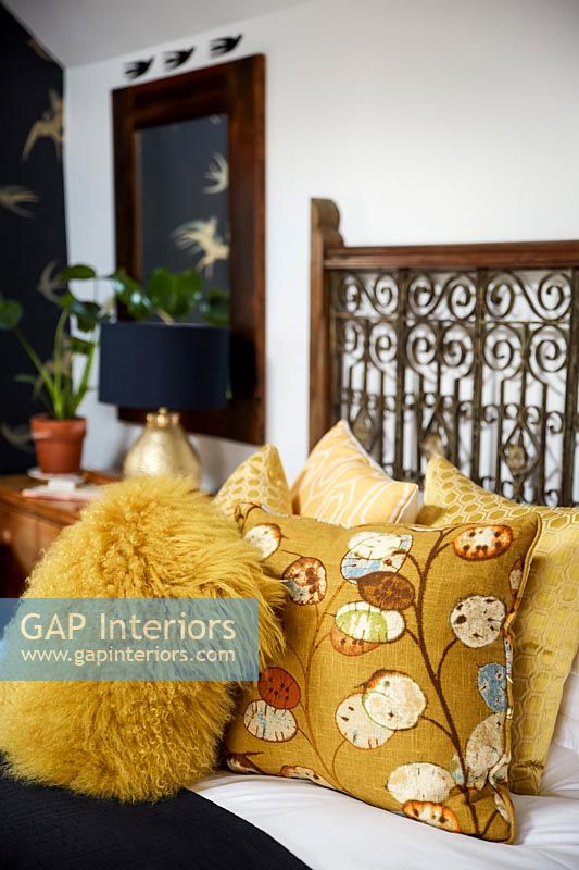 Yellow cushions with ornate bed frame