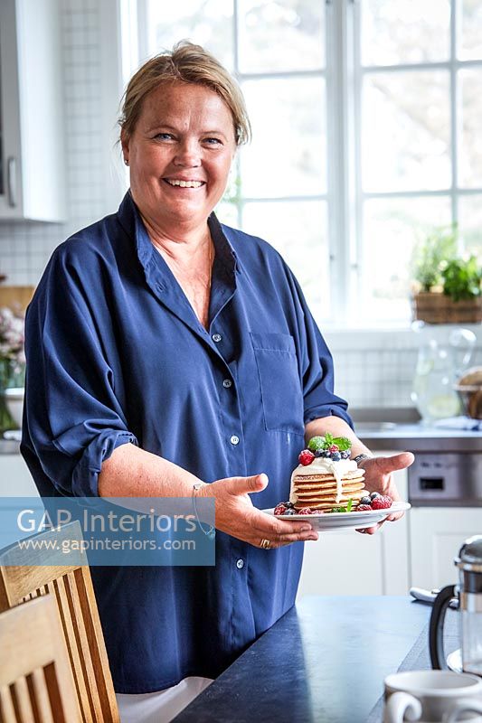 Woman holding plate of pancakes in classic country kitchen