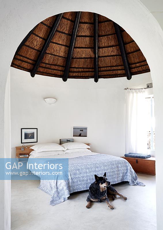 Bedroom with thatched roof and pet dog