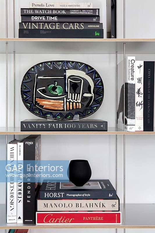 Modern bookshelves with books and decorative plate