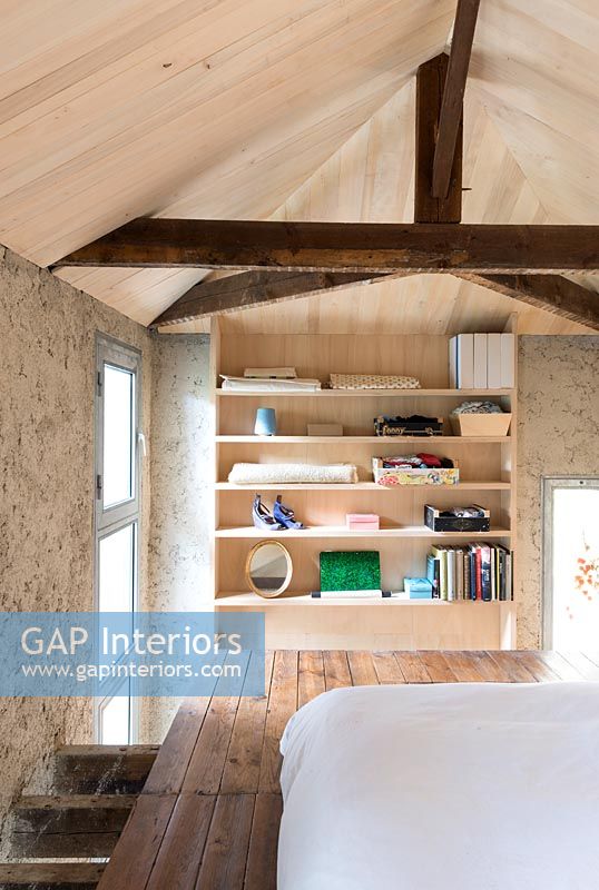 Shelves in modern wooden bedroom with exposed beams and wooden ceilings 