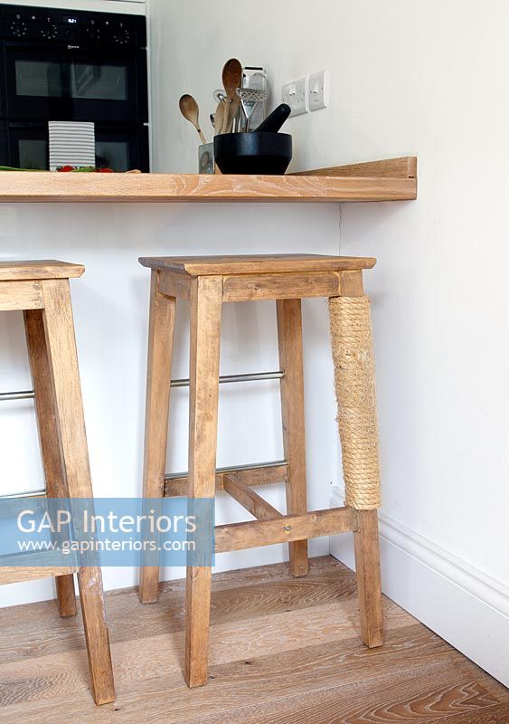Wooden bar stools with a cat scratching post on one stool leg