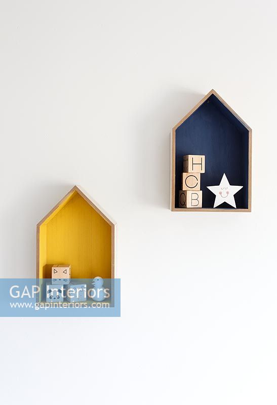 Wall-mounted house shaped frames with wooden toys inside