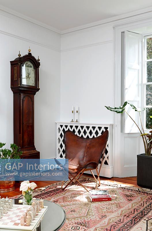 Grandfather clock and leather wing chair in eclectic living room 