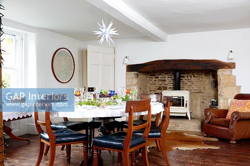 Country dining room with log burning stove in large fireplace 