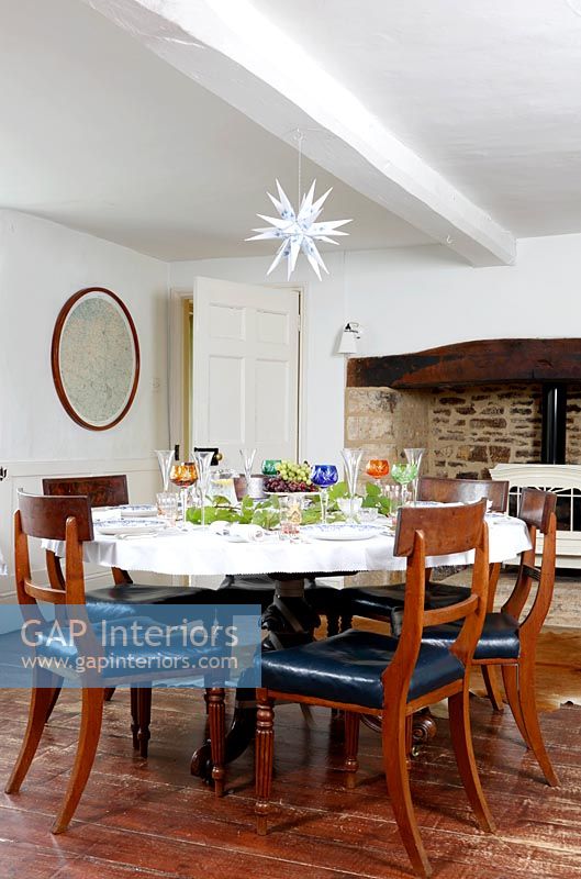 Country dining room with log burning stove in large fireplace 