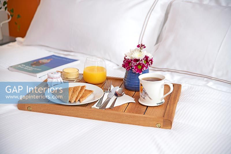 Breakfast tray with flowers and toast on bed 