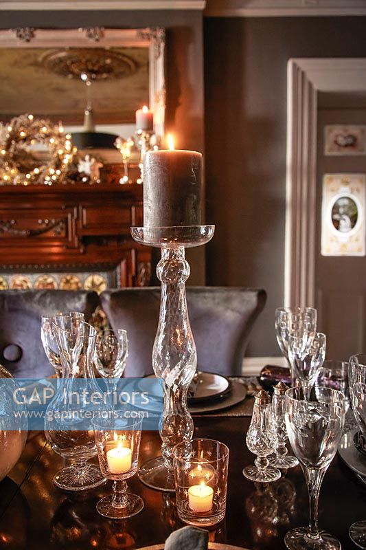 Glass candle stick on classic dining table laid for Christmas dinner 