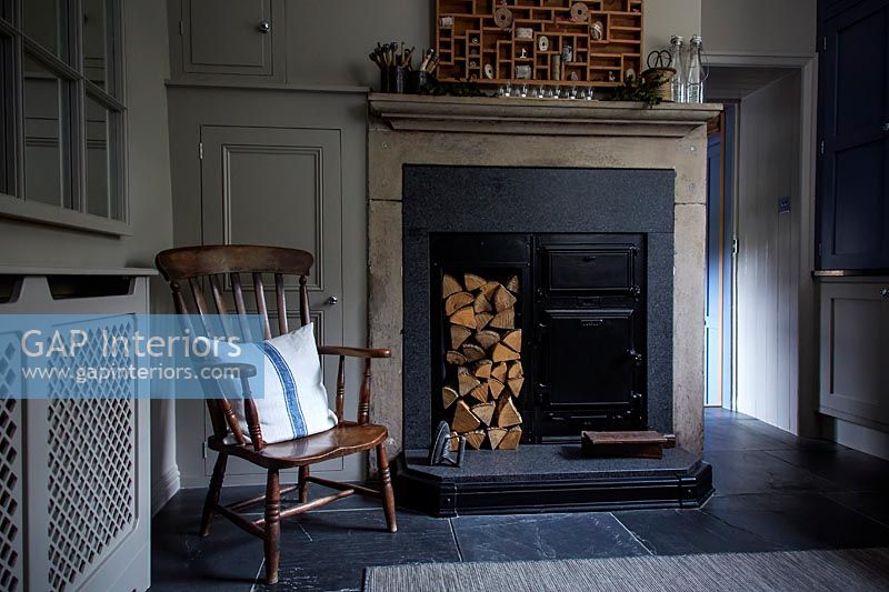 Wooden armchair next to wood burner and log store in fireplace 