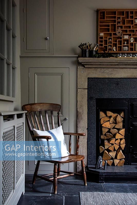 Wooden armchair next to log store in fireplace 